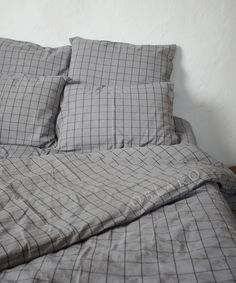 an unmade bed with grey and white checkered sheets