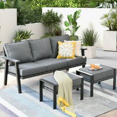 an outdoor patio with grey furniture and potted plants