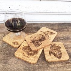 four wooden coasters with drawings on them next to a glass of wine