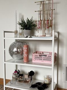 a white shelving unit with various items on it and a mirror ball hanging from the wall