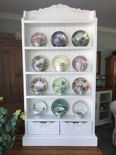 a white china cabinet with many plates on it