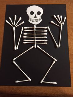 a skeleton made out of sticks on top of a black paper sheet with white paint