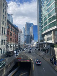 cars are driving through a tunnel in the middle of a busy city street with tall buildings on both sides