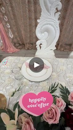 the table is decorated with pink flowers and white plates on it, along with a sign that says happily ever after