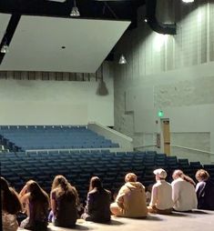 several people sitting on the floor in front of an empty auditorium