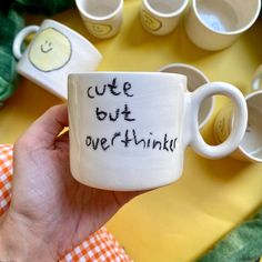 a hand holding a coffee mug with the words cute but overthik written on it