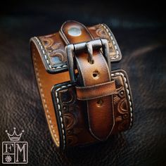 "This leather cuff watch is made using fine quality vegetable tanned leather that is dyed western brown sunset fade. It features a hand tooled and stamped western border and handstitched edges and watch tabs. It uses hand distressed rivets and screws and closes with a hand aged roller buckle. A classic Q&Q watchface by Citizen watch co., with a black face and water resistant movement sits atop! I'll need your wrist size for this watch. Please use the instructions in the above pics! It can be Leather Concho Cuff Bracelet, Leather Cuff Bracelet With Concho, Vintage Hand Tooled Cuff Leather Bracelet, Vintage Hand Tooled Leather Cuff Bracelet, Western Style Hand Tooled Leather Bracelets, Western Brown Hand-tooled Leather Bracelet, Western Leather Concho Cuff Bracelet, Stamped Leather Vintage Cuff Bracelet, Vintage Stamped Leather Cuff Bracelet