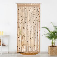 a bamboo curtain hanging on the side of a wall next to a potted plant