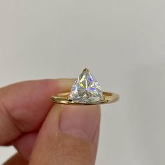 a hand holding a gold ring with a diamond in it's middle and the center