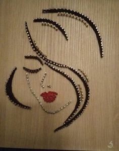 a woman's face is made out of beads and other jewelry on a table