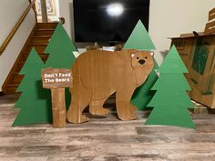 there is a cardboard bear next to some trees on the floor and a tv in the background