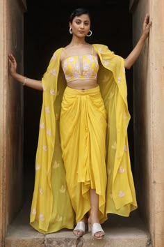 Yellow floral embroidered cape in sequins, cutdanas and bead work. Comes with padded embroidered bustier and draped skirt.
Components: 3
Pattern: Embroidery
Type Of Work: Sequins, Cutdana, Beads
Neckline: Cape: Open, Bustier: Notched
Sleeve Type: Cape: Split, Bustier: Sleeveless
Fabric: Uppada Silk, Georgette, Crepe
Color: Yellow
Other Details: 
Attached lining
Closure: Skirt: Button
Approx weight (in kgs): 2-3
Occasion: Mehendi and Haldi - Aza Fashions Asymmetric Cape, Haldi Ceremony Outfit, Yellow Iris, Mehndi Outfits, Sequin Cape, Haldi Outfits, Haldi Outfit, Long Cape, Beaded Skirt