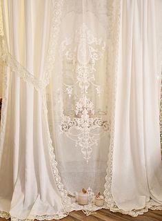 a white curtain with lace trim hanging from it's sides in front of a window