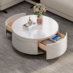 a white coffee table with an open drawer underneath it and flowers in vase on top