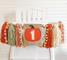 an orange and white pumpkin banner with tassels hanging from it's back