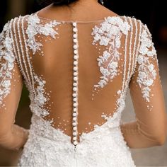 the back of a woman's wedding dress with beaded details and pearls on it