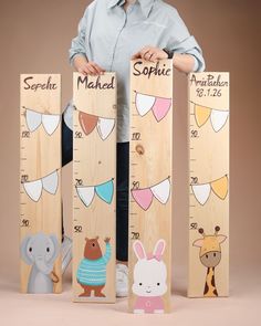 a woman standing next to wooden rulers with animals on them