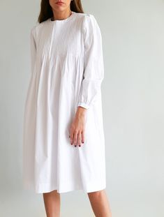 "✨ DETAILS White oversized midi dress with top pleated bodice detail. Featuring a round neckline and long sleeves. Back buttons. Mid calf length. Lightweight fabric. Handmade in Bali: 100% Cotton ✨ CARE INSTRUCTIONS Hand wash in cool water or gentle wash machine - Air Dry ✨ SIZE Model measurements (wearing size S) Height - 1.72 m / 5' 8\" Bust - 86 cm / 34 in Waist - 63 cm / 25 in Hips - 91 cm / 36 in ✨ SHIPPING Please leave a note with a phone number when making a purchase since it might be nee White Long Sleeve Dress With Pleated Sleeves, White Pleated Dress For Daywear, Chic Long Sleeve Dress With Pintucks, White Pleated Sleeve Work Dress, White Pleated Sleeve Dress For Work, White Fall Dress With Gathered Sleeves, White Fall Dresses With Gathered Sleeves, White Dresses With Gathered Sleeves For Fall, White Pleated Midi Dress For Daywear