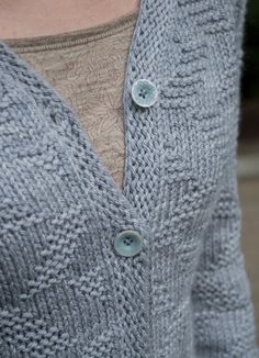 a close up of a person wearing a cardigan sweater with buttons on the front