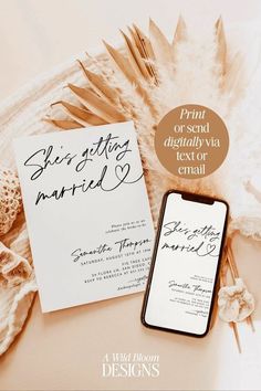 the wedding stationery is displayed next to an open cell phone and seashells