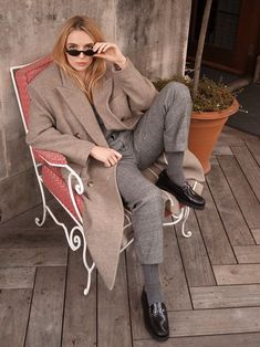 a woman sitting on top of a chair next to a potted plant and wearing sunglasses