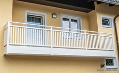 an apartment building with white balconies on the second floor and balcony railings