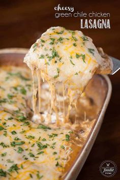 cheesy green chile chicken lasagna is being lifted from a casserole dish