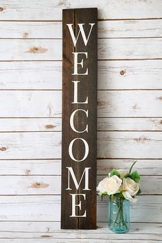 a wooden welcome sign next to a vase with flowers