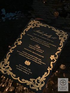 a black and gold wedding card on top of some coins