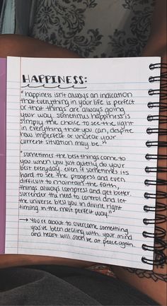 someone holding up a notebook with the words happiness written in cursive writing on it