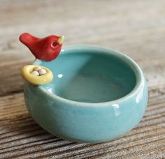 a small blue bowl with a red bird in it