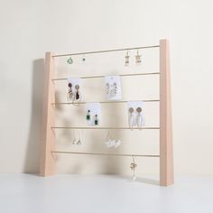 a wooden display with earrings and earring hooks on it's sides against a white wall