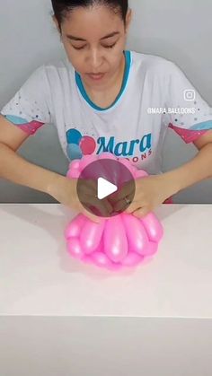 a young woman is playing with an inflatable pink toy on a white table