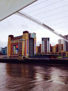 a bridge over water with buildings in the background and a body of water below it