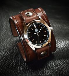 "Crafted from premium Full grain Italian bridle leather, this elegant cuff watch features a rich brown hue.  Measuring 2\" in width, the edges are finely scribed for a polished look. The watchtabs, adorned in matching brown, are handstitched, fastening with an aged roller buckle.  At its heart lies a timeless FM watchface with a sleek black face, complemented by its water-resistant Japanese, super Miyota movement, sapphire crystal and 316L stainless case to withstand various conditions.  I requi Masculine Brown Watch Accessories With Subdials, Brown Watch Accessories With Subdials, Brown Watch With Bracelet Strap And Round Dial, Masculine Brown Leather Strap Watch, Rugged Brown Leather Watches, Classic Brown Leather Bracelet For Formal Occasions, Timeless Brown Watch With Bracelet Strap, Brown Formal Watches With Bracelet Strap, Formal Brown Watches With Bracelet Strap