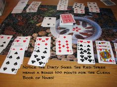 playing cards laid out on top of a wooden table with words written below them that read, notice the dirty skies, the red three means a bones too points for the clean book of nines