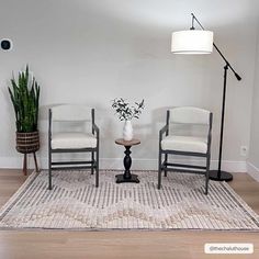 two chairs sitting on top of a rug next to a lamp