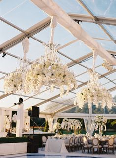 an outdoor wedding venue with chandeliers and tables set up for the guests to eat