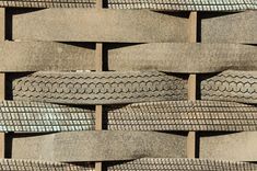 several tires stacked on top of each other in front of a brick wall or fence