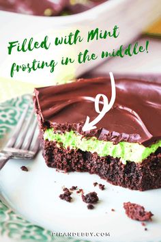 a piece of chocolate cake with green frosting on a plate next to a fork