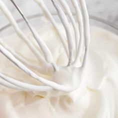 a whisk in a glass bowl filled with whipped cream