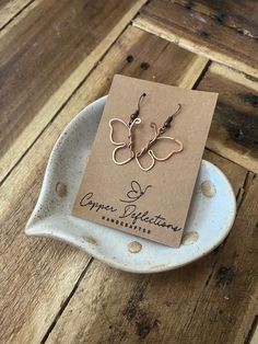 Looking for a unique piece of jewelry that's both beautiful and long-lasting? Look no further than our Copper Butterfly Earrings! These handmade dangle earrings are perfect for the one-of-a-kind person in your life who loves one-of-a-kind pieces. Crafted with care and attention to detail, these earrings are made to last. They're small enough to be worn daily, yet beautiful enough to make a statement. And as they age, they develop a natural patina that only adds to their charm. Copper is known for its ability to develop this patina over time, adding depth and character with each passing year. And with our simple cleaning process, you can keep your Copper Butterfly Earrings looking great for years on end. So if you're looking for an elegant yet enduring piece of jewelry that's sure to turn h Nature-inspired Copper Earrings As Gift, Wire Wrapped Rose Gold Earrings For Gift, Single Copper Earring As Gift, Nature-inspired Jewelry Ear Wire For Gift, Wire Wrapped Earrings As Gift, Single Earring Nature-inspired Jewelry As Gift, Nature-inspired Single Earring As A Gift, Nature-inspired Single Earring As Gift, Mother's Day Earrings Gift For Her