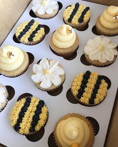 twelve cupcakes decorated with yellow, black and white frosting in a box