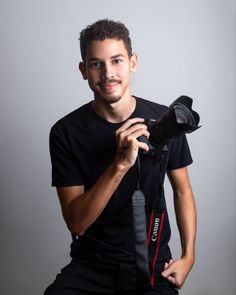 a man is holding a camera and posing for a photo with the flash attached to his shoulder