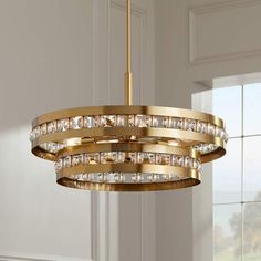 a gold chandelier hanging from a ceiling in a room with white walls and windows