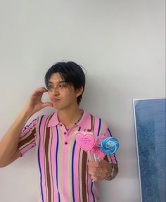 a young man is holding two lollipops in his hand and posing for the camera