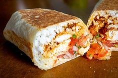 a burrito cut in half sitting on top of a wooden table