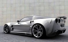 a silver sports car is parked in front of a gray wall and brick flooring