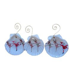 two white plates with red designs on them and wire hangers in the shape of santa's sleighs