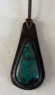 "Leather Necklace with Semi Precious Chrysocolla Cabochon. The leather is cut and wet molded over the cabochon. The two layers of leather are handstitched together and the edges are dyed and waxed.  The rolled leather cord is 20\" long with a stainless steel clasp.  This pendant measures 2 7/8\" tall and 1 1/2\" wide. Handmade in California" Southwestern Turquoise Leather Jewelry, Handmade Leather Necklace In Brown, Vintage Leather Jewelry With Patina, Brown Leather Jewelry With Patina, Green Leather Artisan Jewelry, Southwestern Brown Leather Jewelry, Vintage Leather Jewelry With Strap, Green Leather Jewelry Gift, Green Leather Jewelry For Gifts